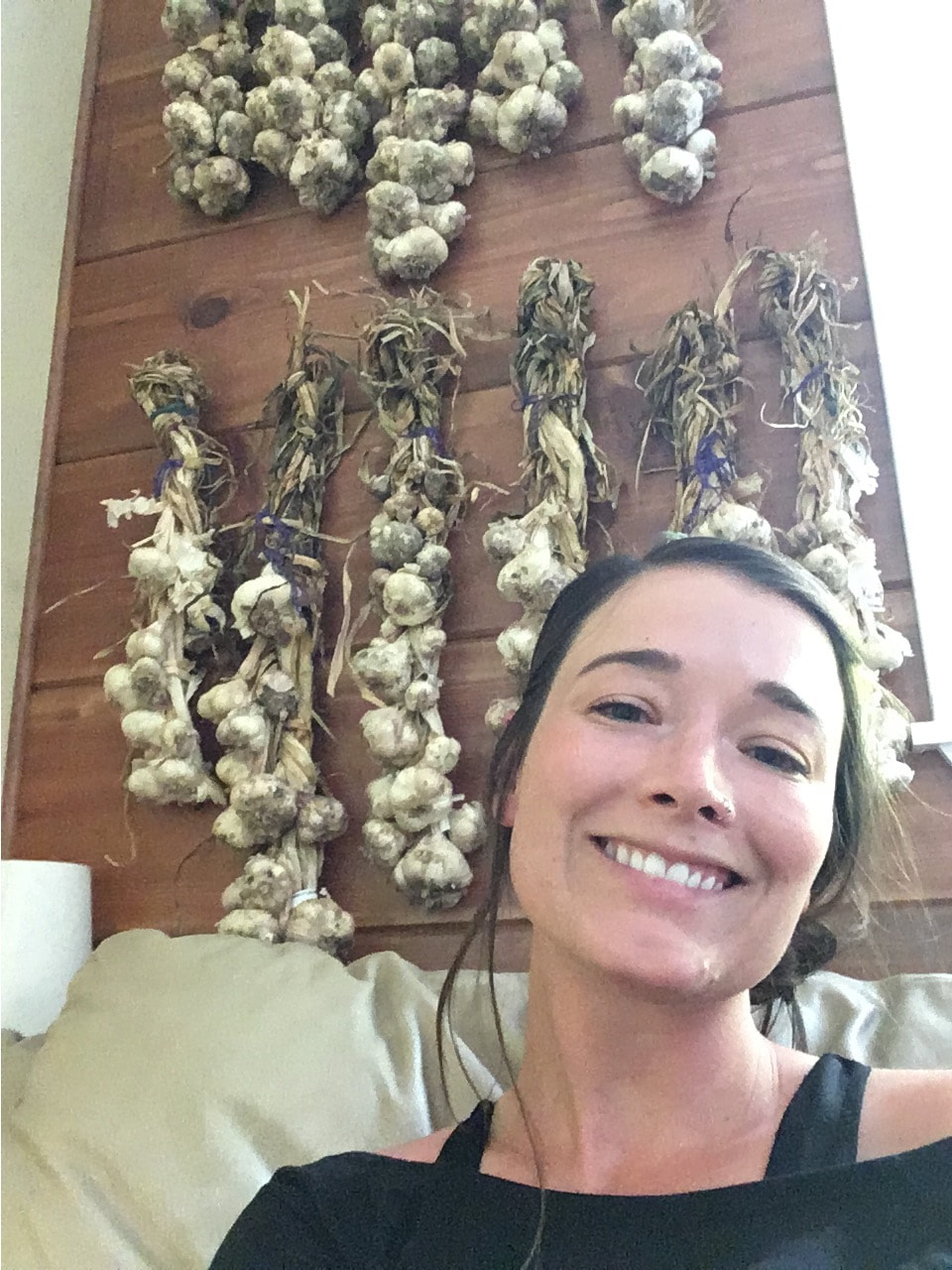 A picture of Ms. Allie at home posing with her garlic harvest.